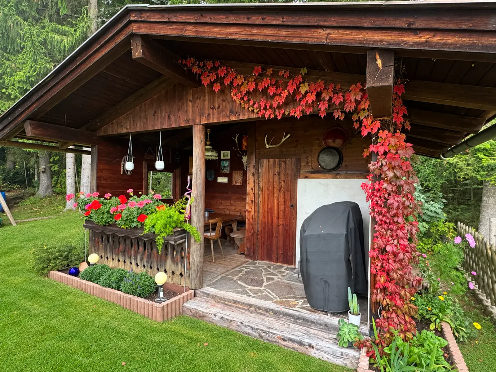 Gemütliches hölzernes Gartenhaus mit Blumen und Sitzplätzen